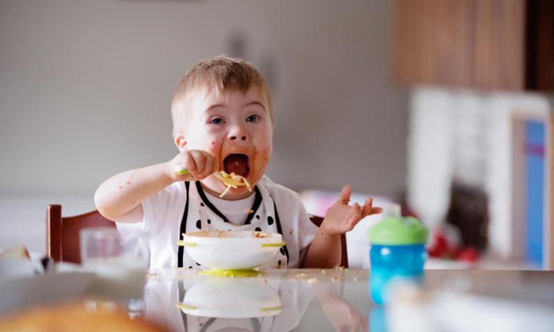 Criança com síndrome de Down comendo